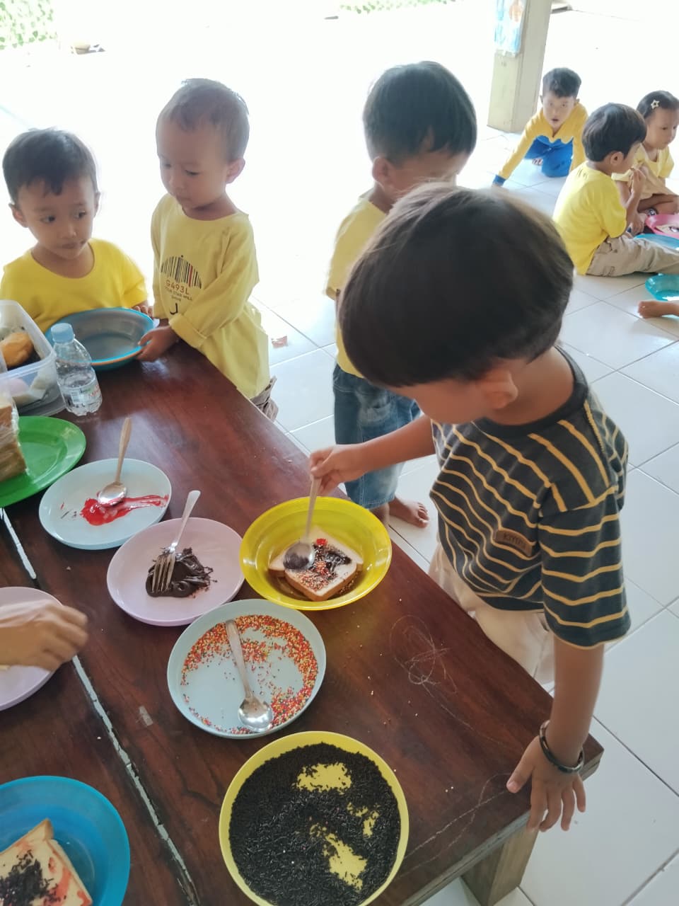 Murid murid mengaplikasikan selai ke roti